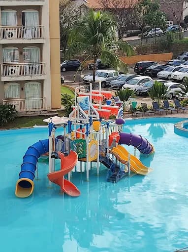Piscina infantil com toboáguas e brinquedos aquáticos coloridos.