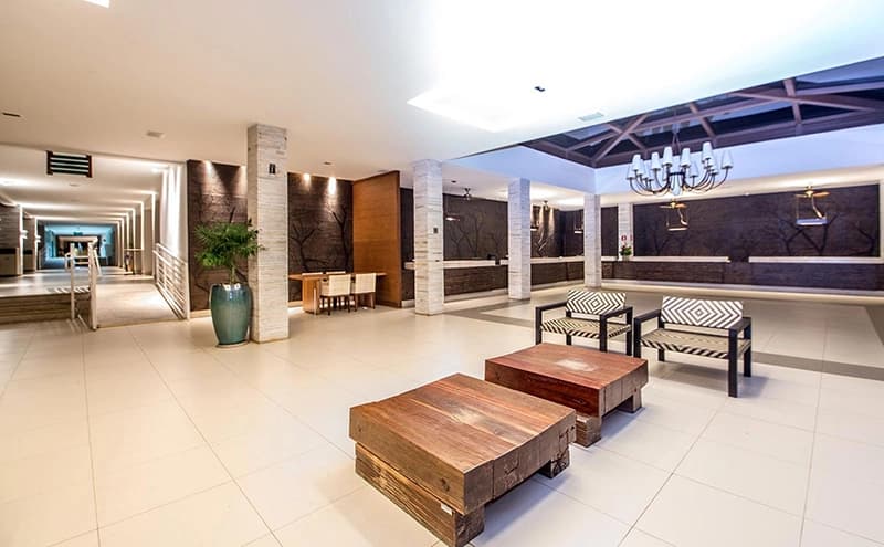Lobby do hotel com poltronas e mesas de centro em estilo baú.
