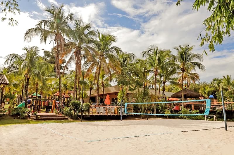 Área externa do resort com piscinas, palmeiras e jardins.