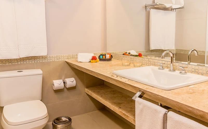 Banheiro de um apartamento com ampla bancada de madeira e espelho.