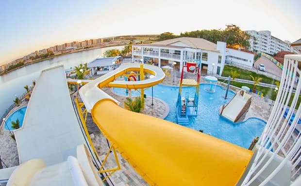 Piscina de borda infinita com vista para o lago ao entardecer.