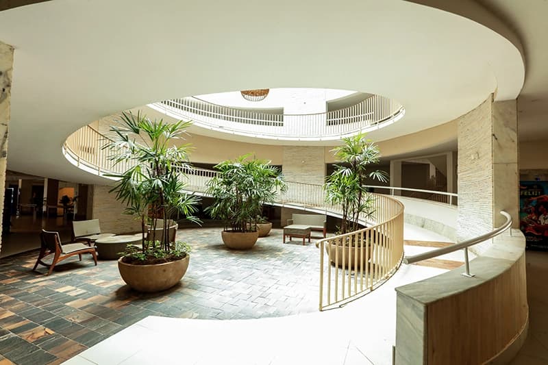 Lobby do hotel com arquitetura em formato circular e plantas.