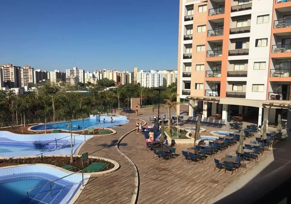 Quarto de casal decorado com varanda e vista para as piscinas.