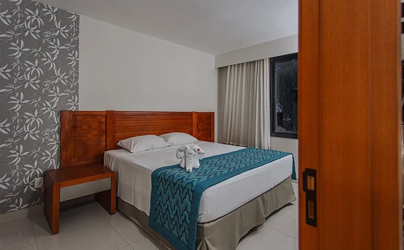 Quarto de hotel com uma cama de casal e cabeceira estofada.