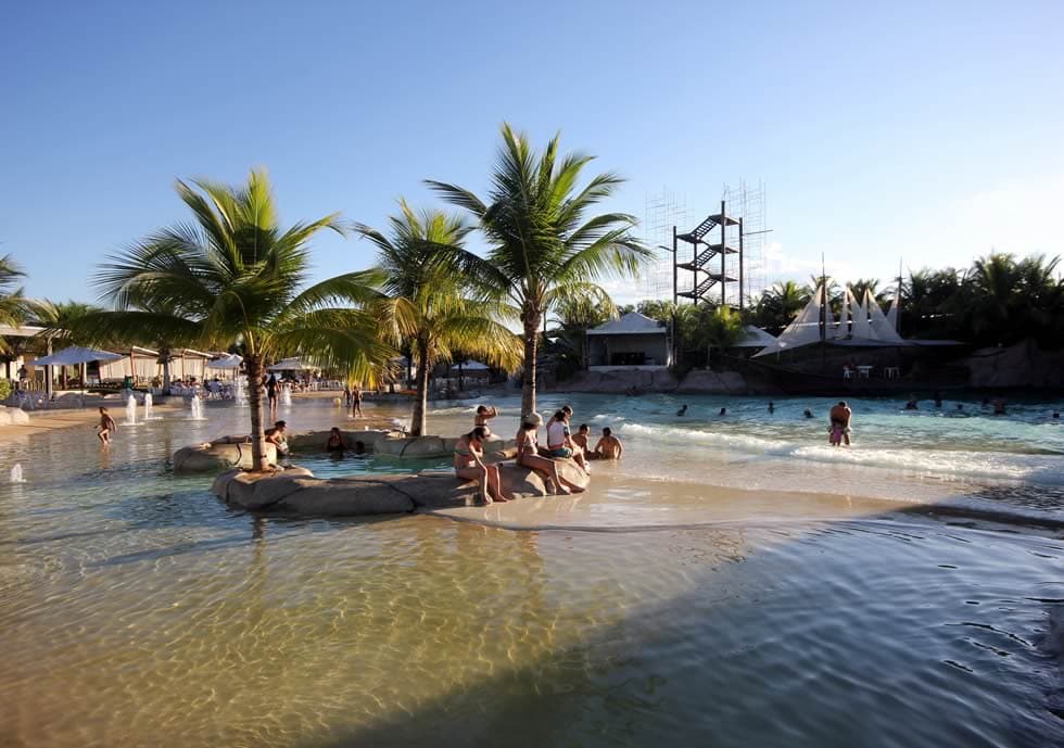 Bar molhado com pessoas relaxando em bancos submersos.