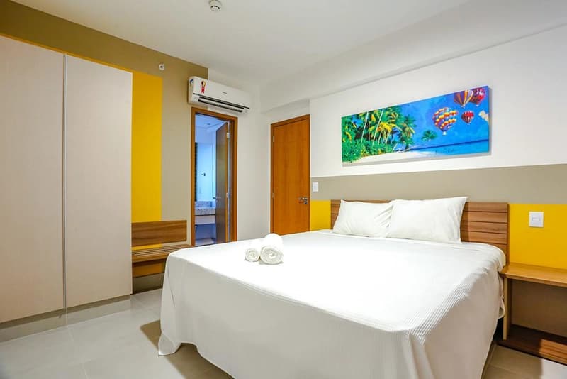 Quarto de casal com parede em destaque na cor amarela.