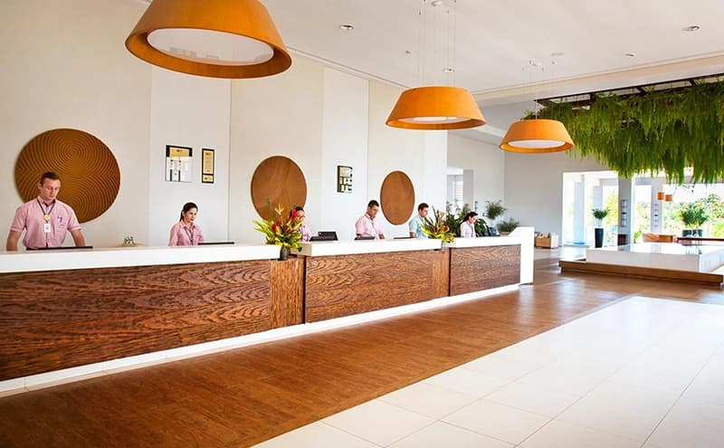 Balcão de recepção do hotel com design moderno e iluminação laranja.