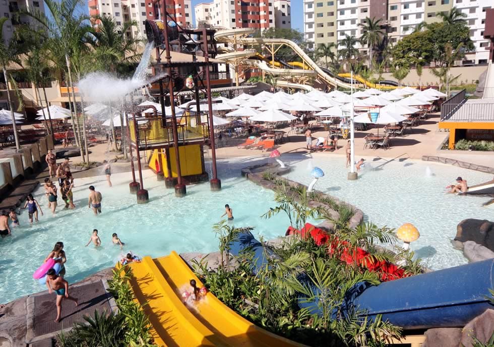 Crianças brincando na área infantil com playground aquático.