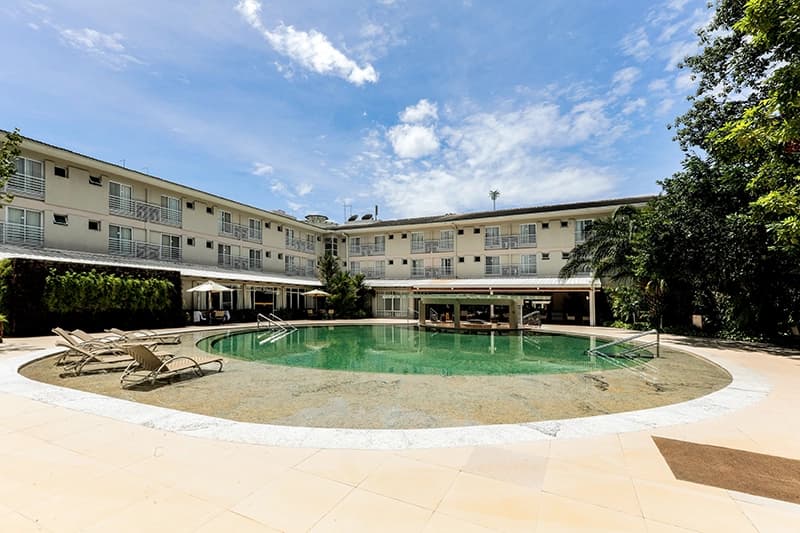 Piscina do hotel com o prédio de arquitetura clássica ao fundo.