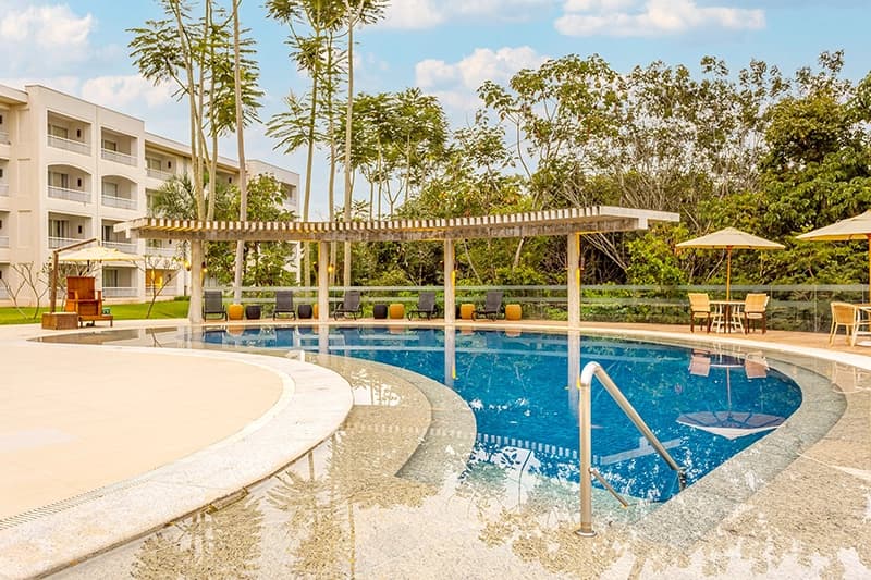 Área de piscina com deck de madeira, espreguiçadeiras e um pergolado.