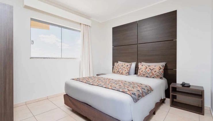 Quarto de hotel decorado com cama de casal e iluminação ambiente.