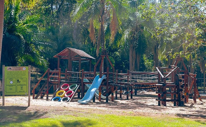 Playground infantil de madeira em meio à área verde.