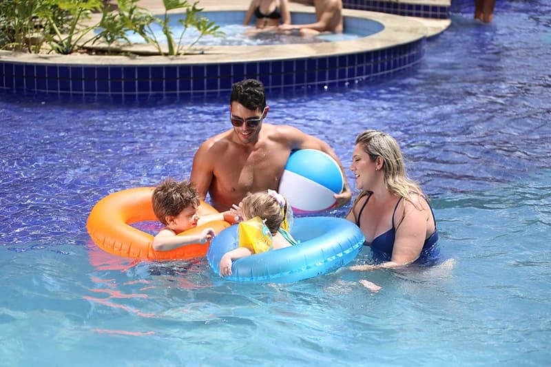 Família se divertindo com boias na piscina do resort.