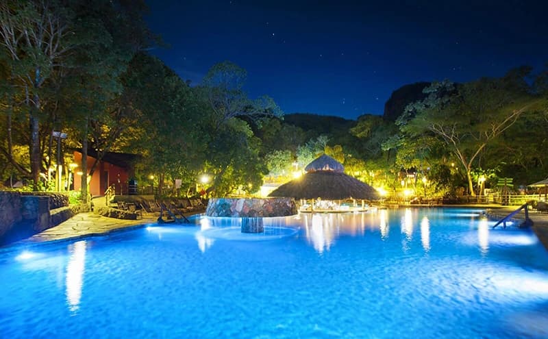 Iluminação subaquática criando um ambiente mágico nas piscinas do Parque das Fontes à noite