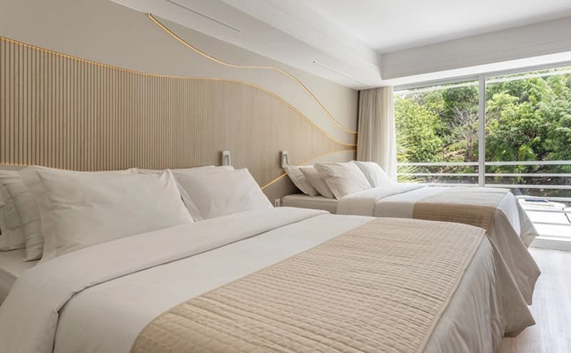 Quarto de casal com cama arrumada e acesso à varanda com vista.