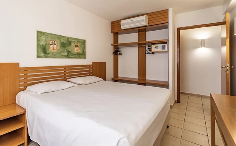 Quarto com cama de casal embutida em móvel de madeira.