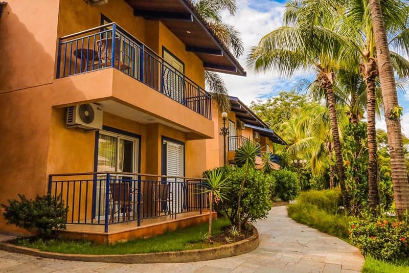 Vista externa de um prédio de apartamentos do resort com sacadas e coqueiros.