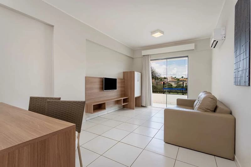Sala de estar de um apartamento do hotel com sofá, TV e acesso à sacada.