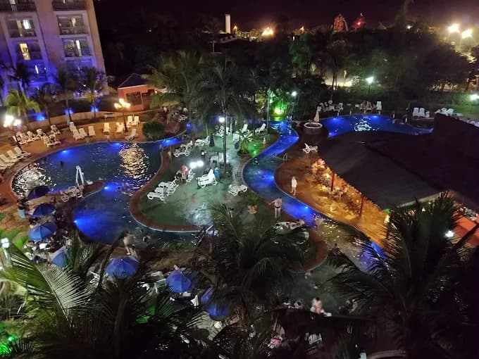 Vista aérea do complexo de piscinas do resort à noite.
