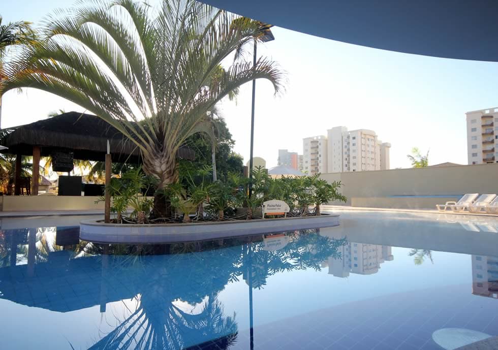 Família sorrindo e se divertindo em uma das piscinas do clube.