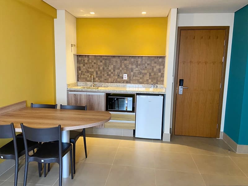 Interior de um apartamento decorado, mostrando a sala e a cozinha gourmet