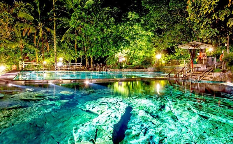 Piscina natural do Parque das Fontes com iluminação subaquática durante a noite