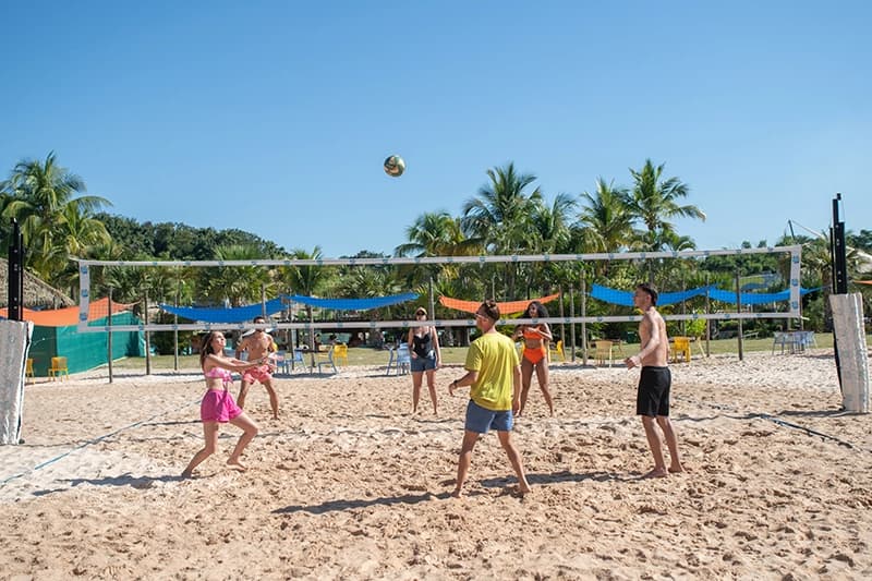 Amigos jogando uma partida de vôlei na areia da Praia do Cerrado.