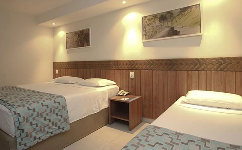 Quarto com duas camas de solteiro e móveis de madeira.