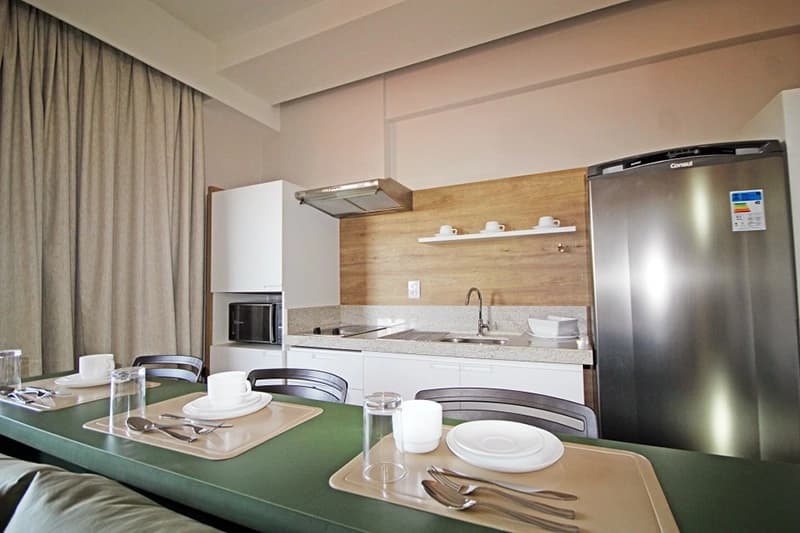 Cozinha completa de um apartamento, com geladeira, fogão e armários.