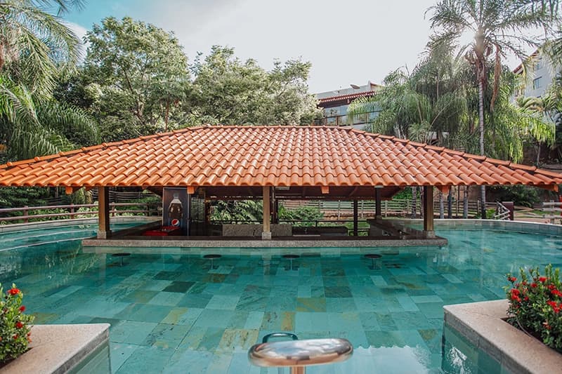 Bar molhado com estrutura de madeira localizado dentro da piscina.