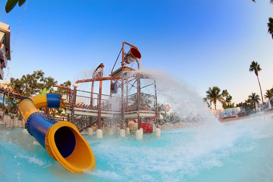 Família aproveitando a praia artificial com areia branca e coqueiros.