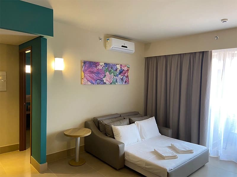 Sala de um apartamento com sofá-cama e vista para a janela.