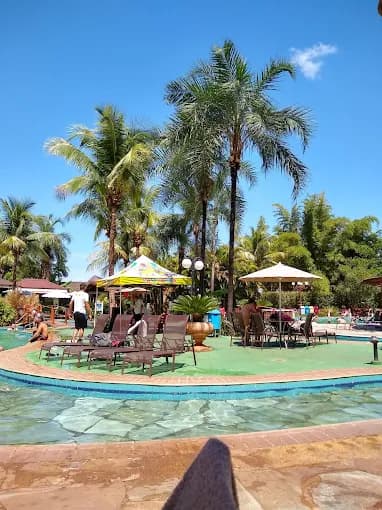 Quiosque com teto de sapé na área de lazer da piscina.