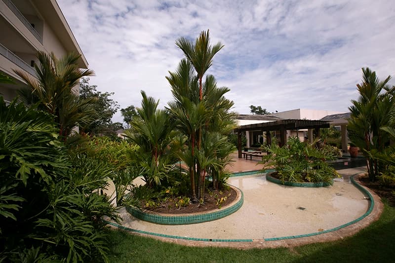 Jardim interno do resort com paisagismo e um pequeno caminho.