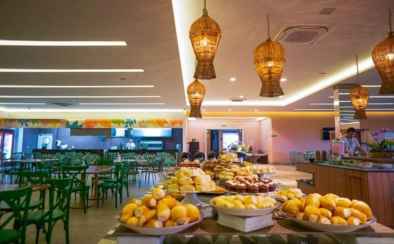 Mesa do buffet com variedade de pães, frios e doces.