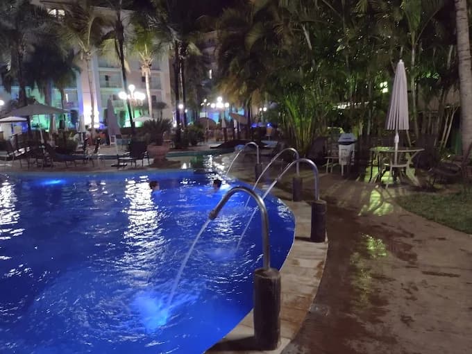 Piscina do resort com intensa iluminação azul durante a noite.