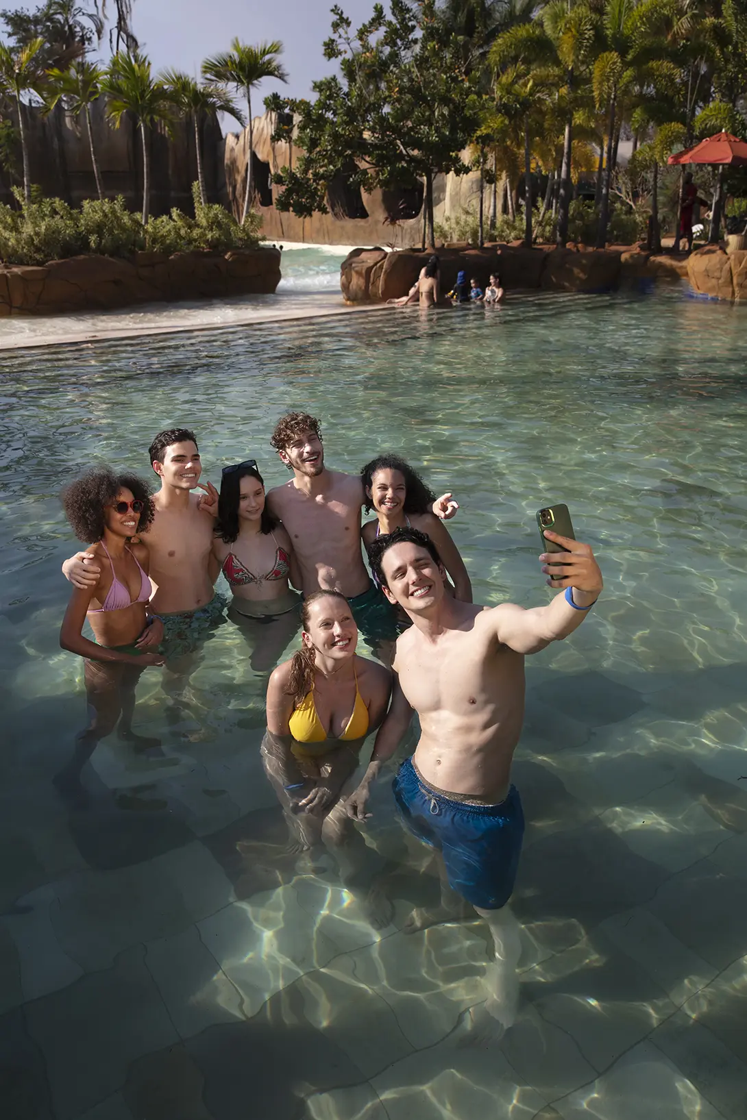 Amigos se divertindo na piscina, com uma mulher sendo erguida pelo grupo.
