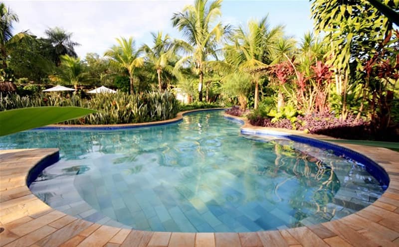 Piscina com área de deck molhado e espreguiçadeiras dentro d'água.