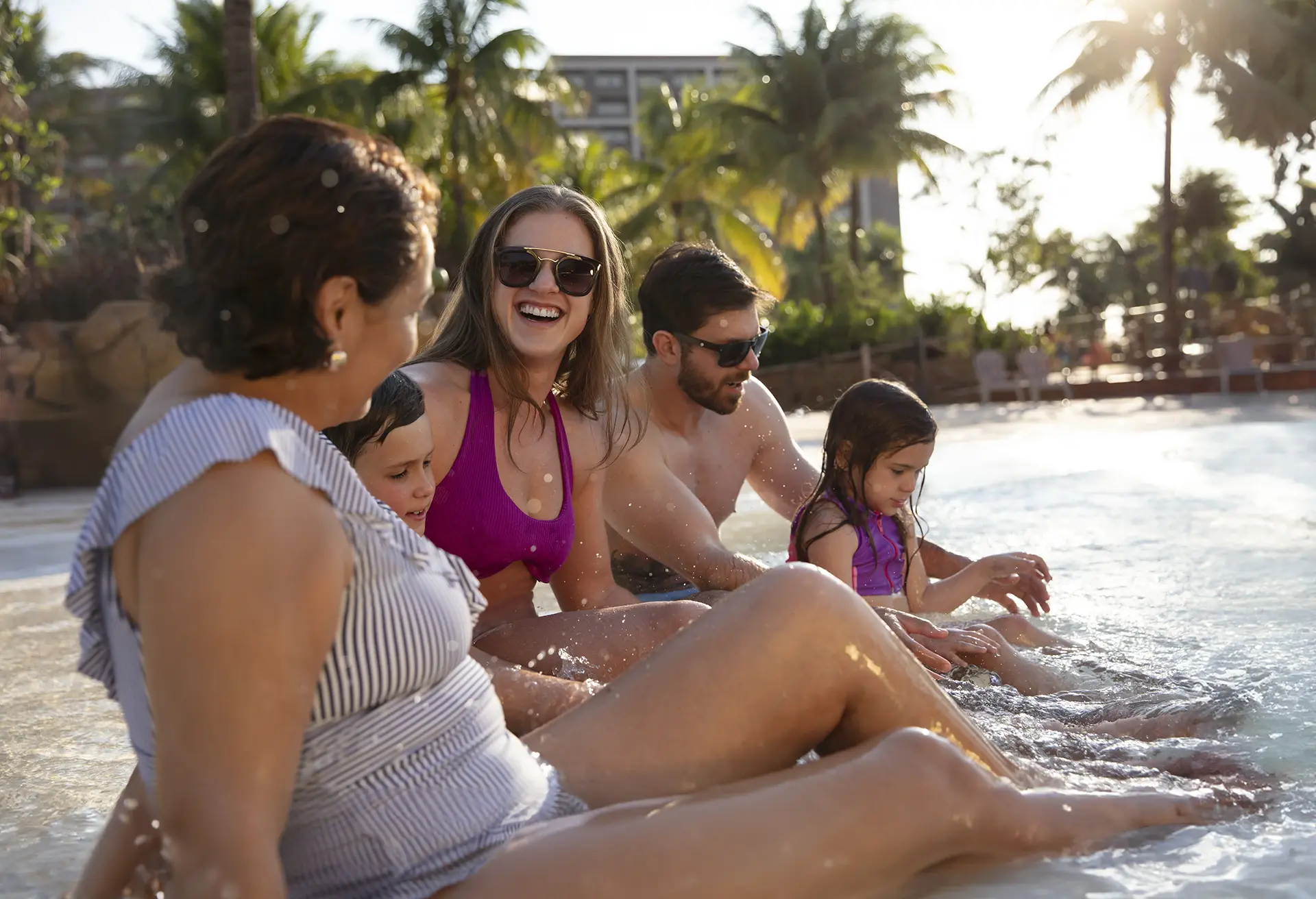 Pai sorrindo enquanto segura seu filho pequeno dentro da piscina.