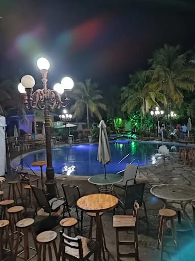 Vista da piscina à noite com postes de iluminação decorativos.