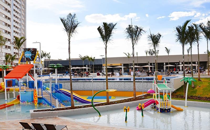 Playground externo com brinquedos e gramado sintético.