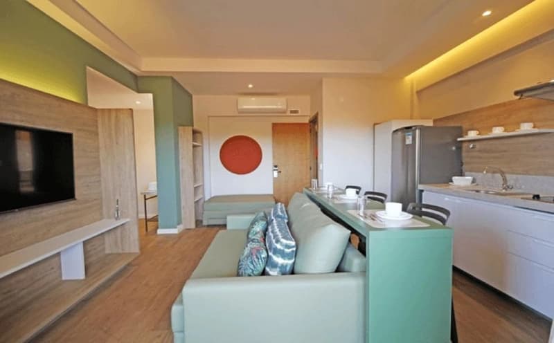 Sala de estar ampla de um apartamento, com sofá, rack e TV.