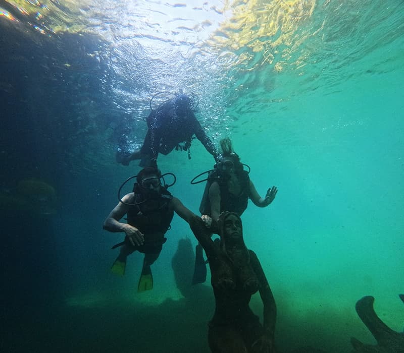 Dois mergulhadores explorando o fundo de um lago de águas claras.