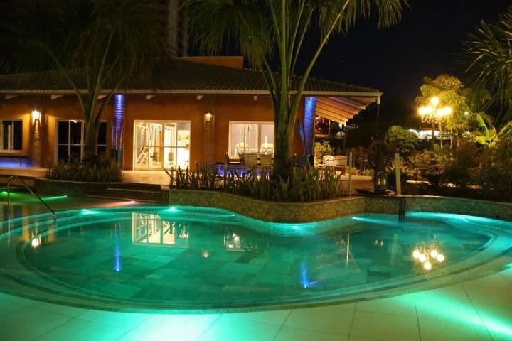Piscina do resort iluminada durante a noite.