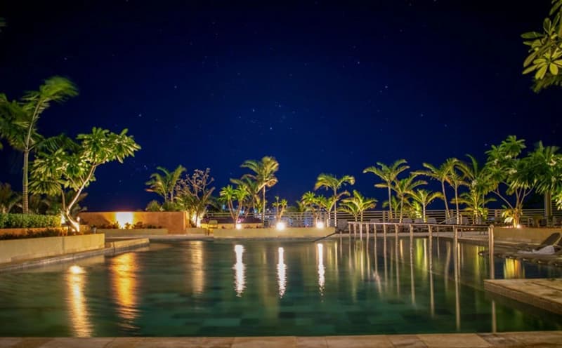 Vista noturna da lagoa ou piscina do resort, com o prédio ao fundo.