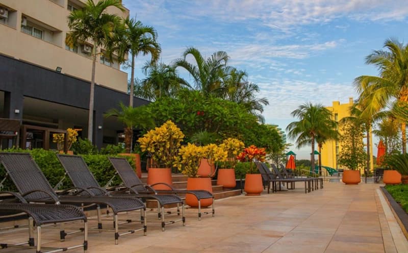 Espreguiçadeiras ao lado da piscina e do jardim do resort.