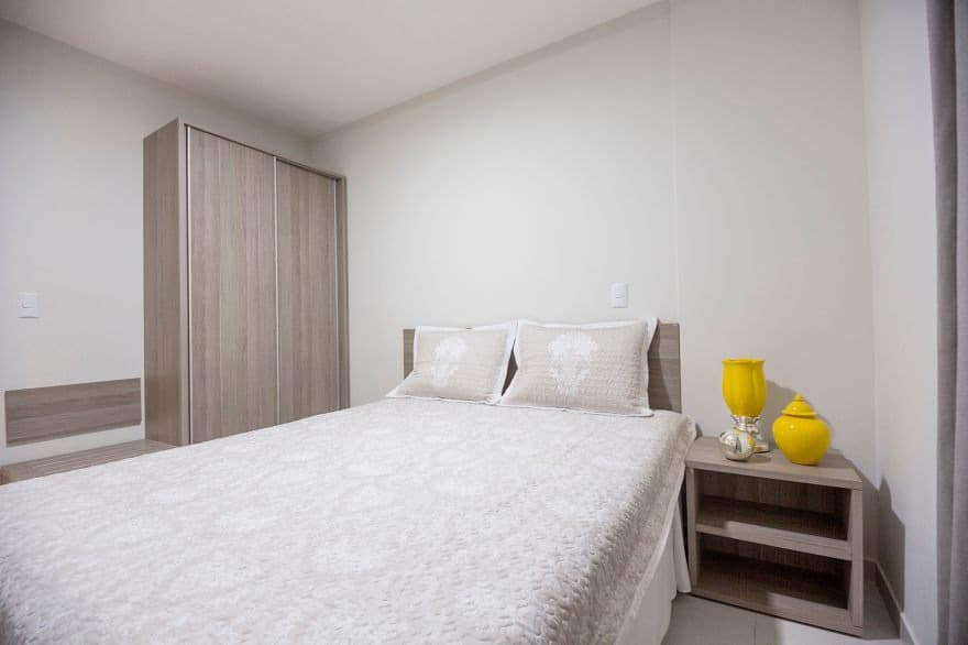 Vista de um dos quartos do apartamento, com cama arrumada.