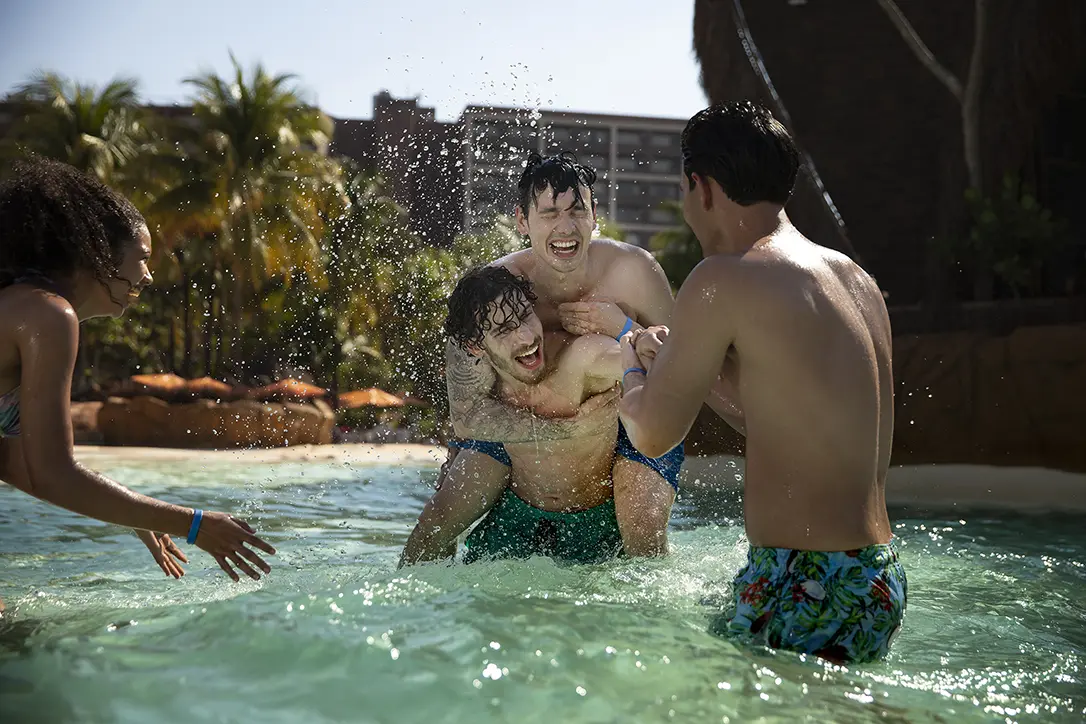 Casal se divertindo na piscina, com o homem segurando a mulher no colo.