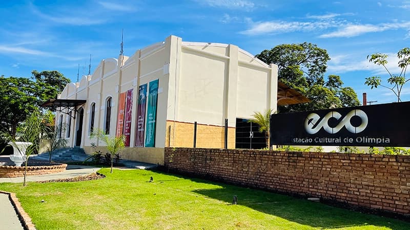 Fachada de prédio histórico branco com gramado em Olímpia