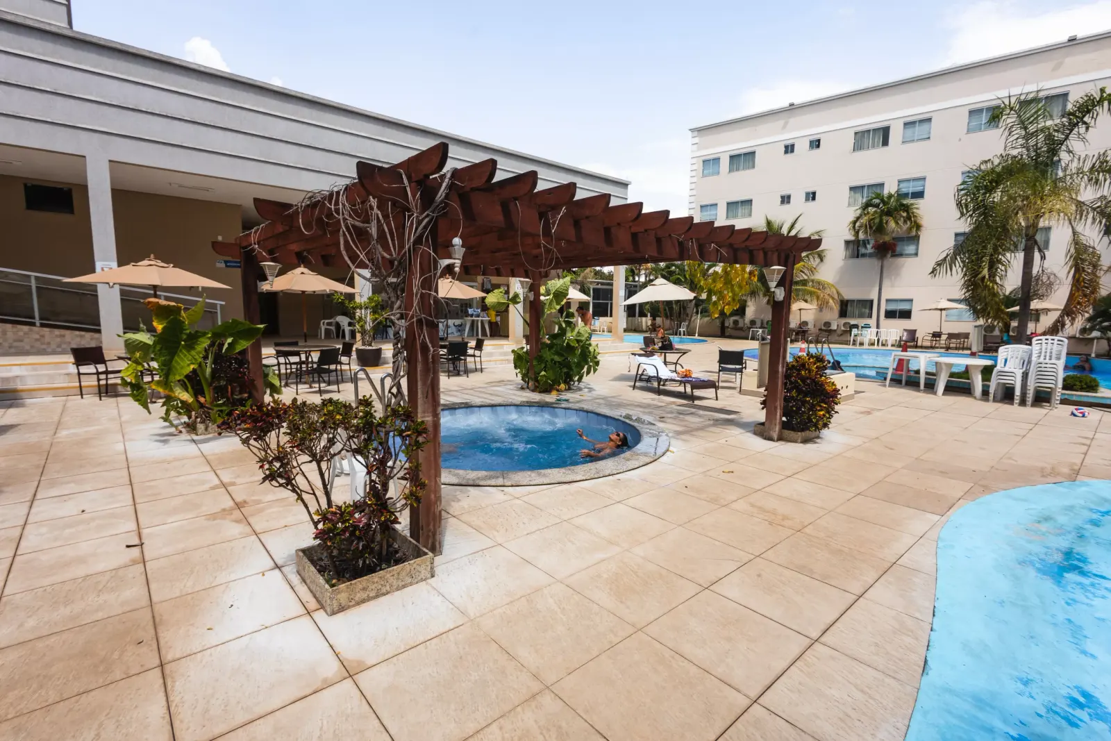 Área de piscinas do resort com espreguiçadeiras e prédios ao fundo